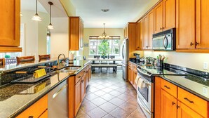 A kitchen with wooden cabinets, a granite countertop, a built-in oven, and a microwave. - Steps to Bay: Tranquil Navarre Retreat w/ Balcony (Navarre)