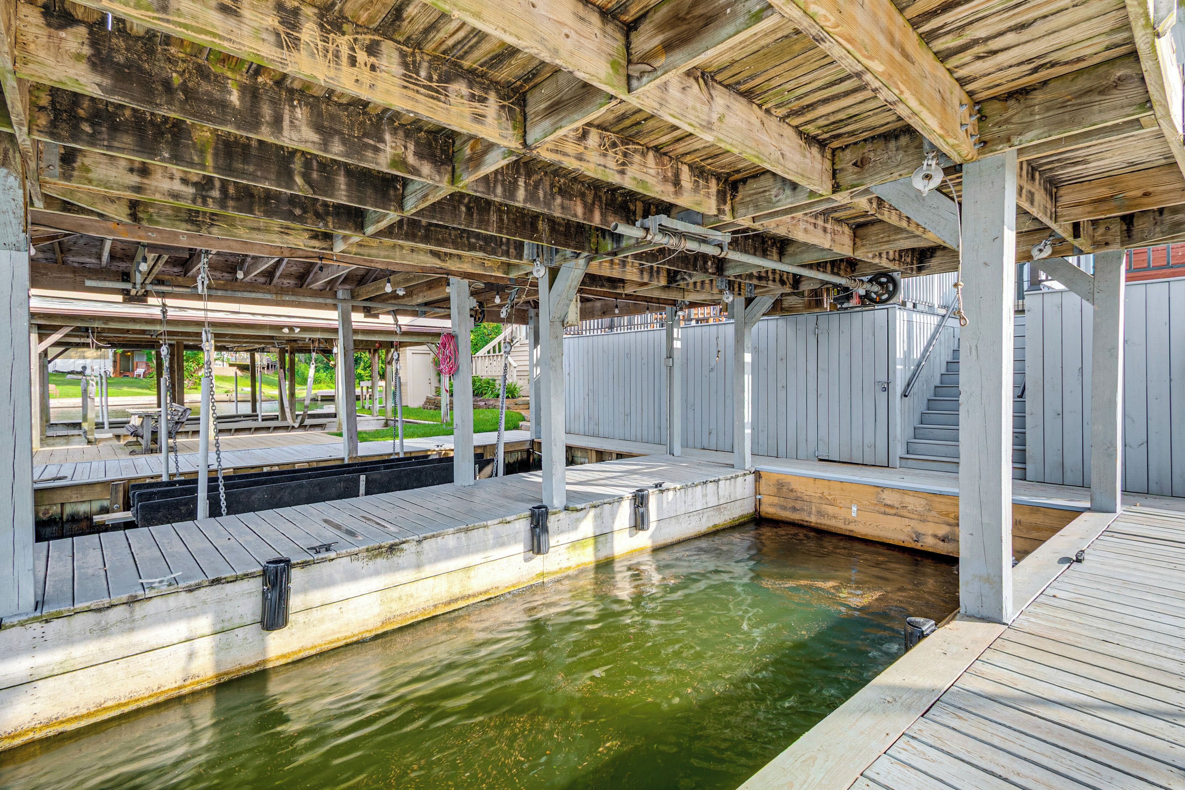 A wooden deck with a pool, wooden railings, and a staircase leading to a covered area.