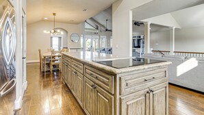 Une cuisine spacieuse dotée de meubles en bois, d’un grand îlot central et d’un coin repas avec des chaises.