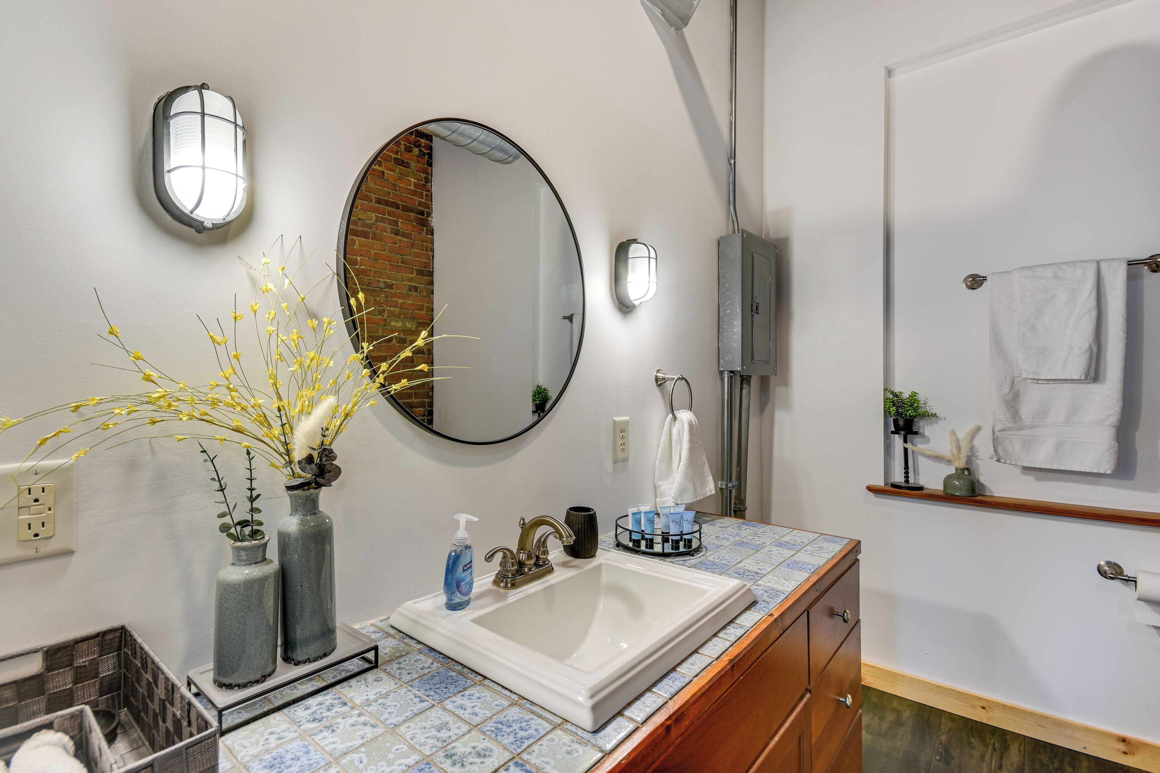A bathroom with a white sink, a round mirror, and a towel rack.