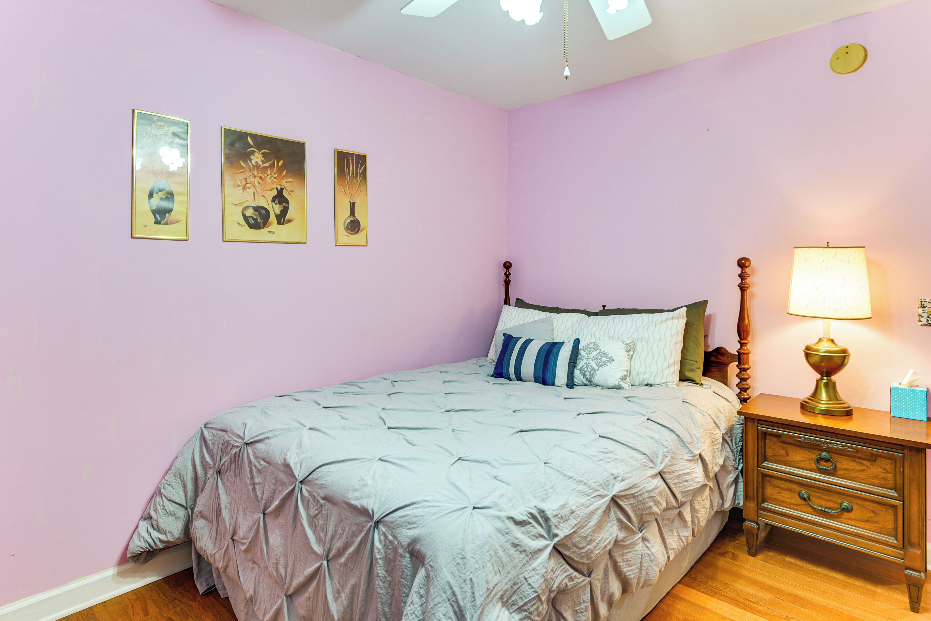 A bedroom with a bed, a nightstand, a lamp, and wall art.