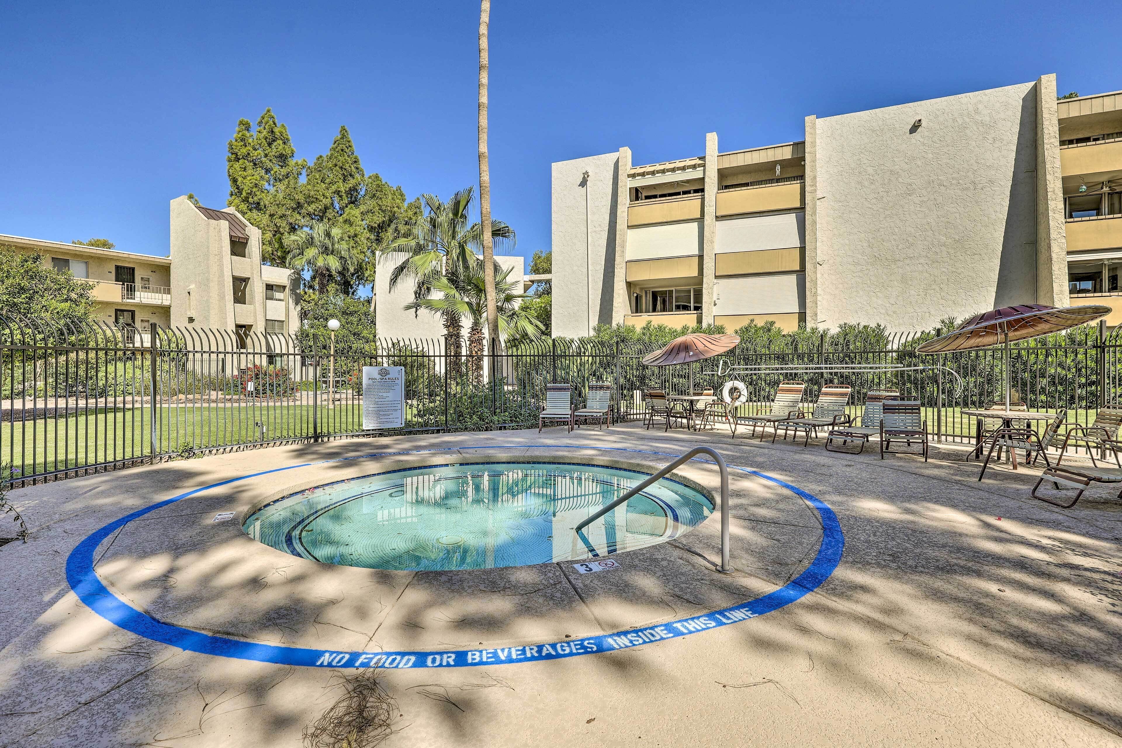 A swimming pool with a 'No Food or Beverages Inside This Lane' sign, surrounded by a fence, palm trees, and a building with multiple balconies.