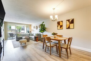 Una sala de estar moderna con comedor, un conjunto de sofás, una mesa de centro y una araña.