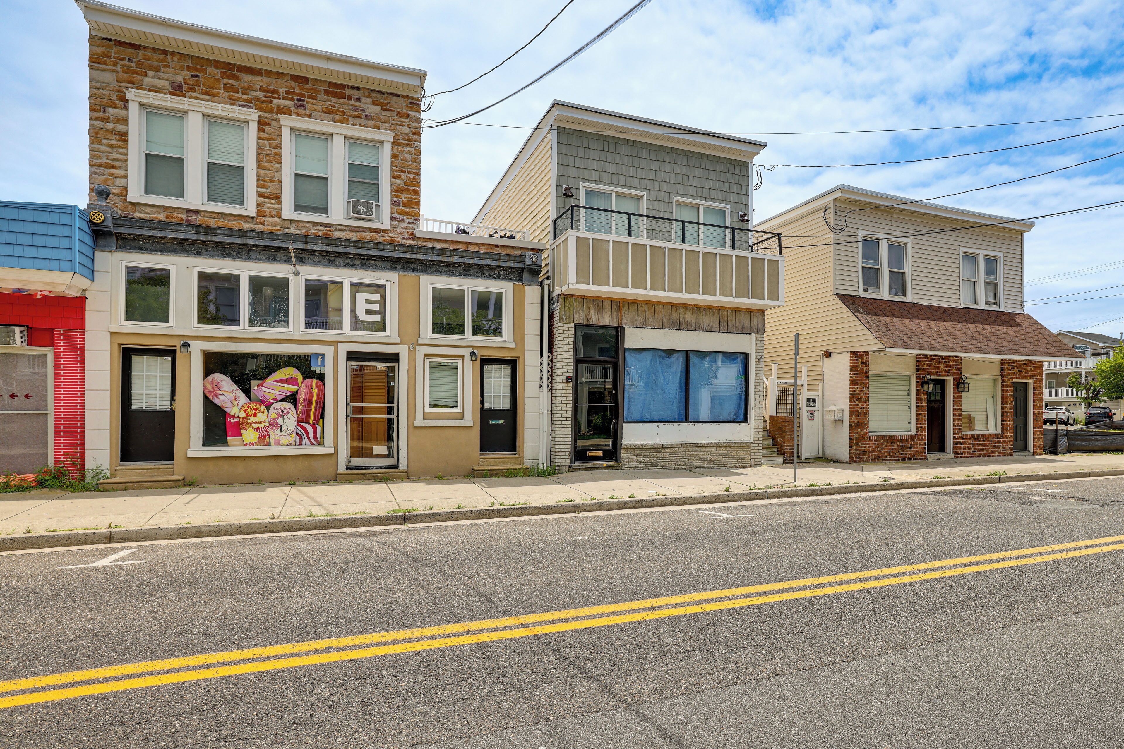 A row of multi-story buildings with various storefronts, including a visible restaurant with a large window display.