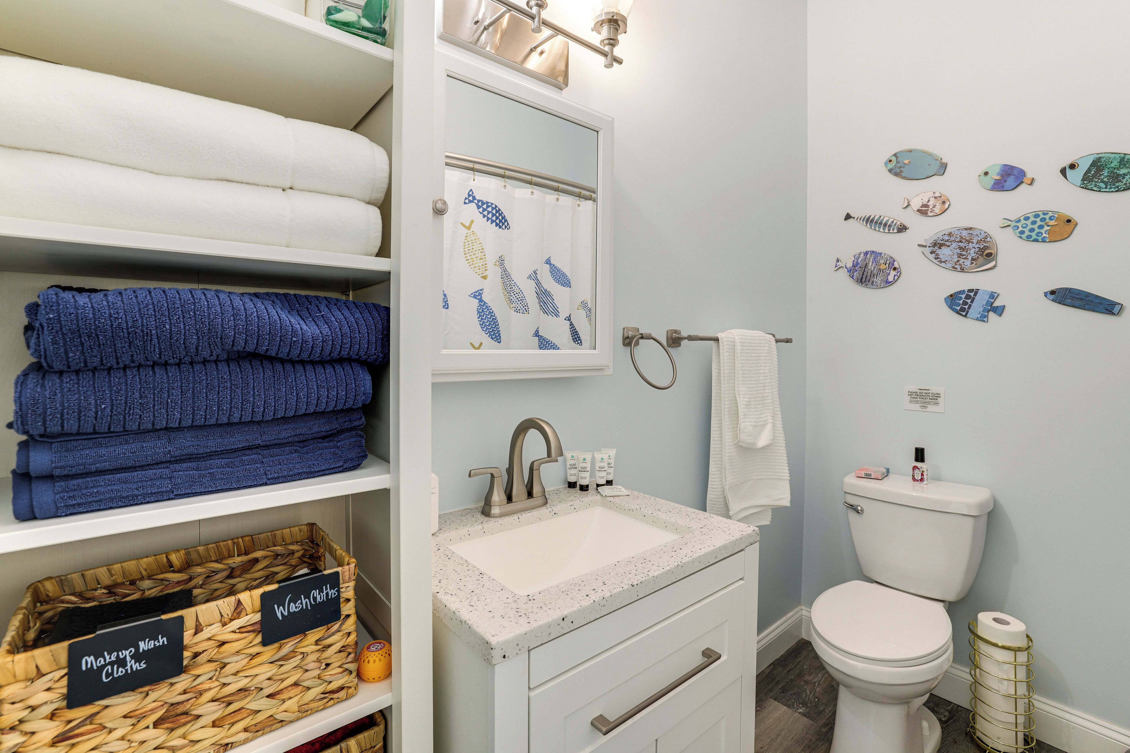 Une salle de bain avec un lavabo, des toilettes et un décor mural représentant des poissons.