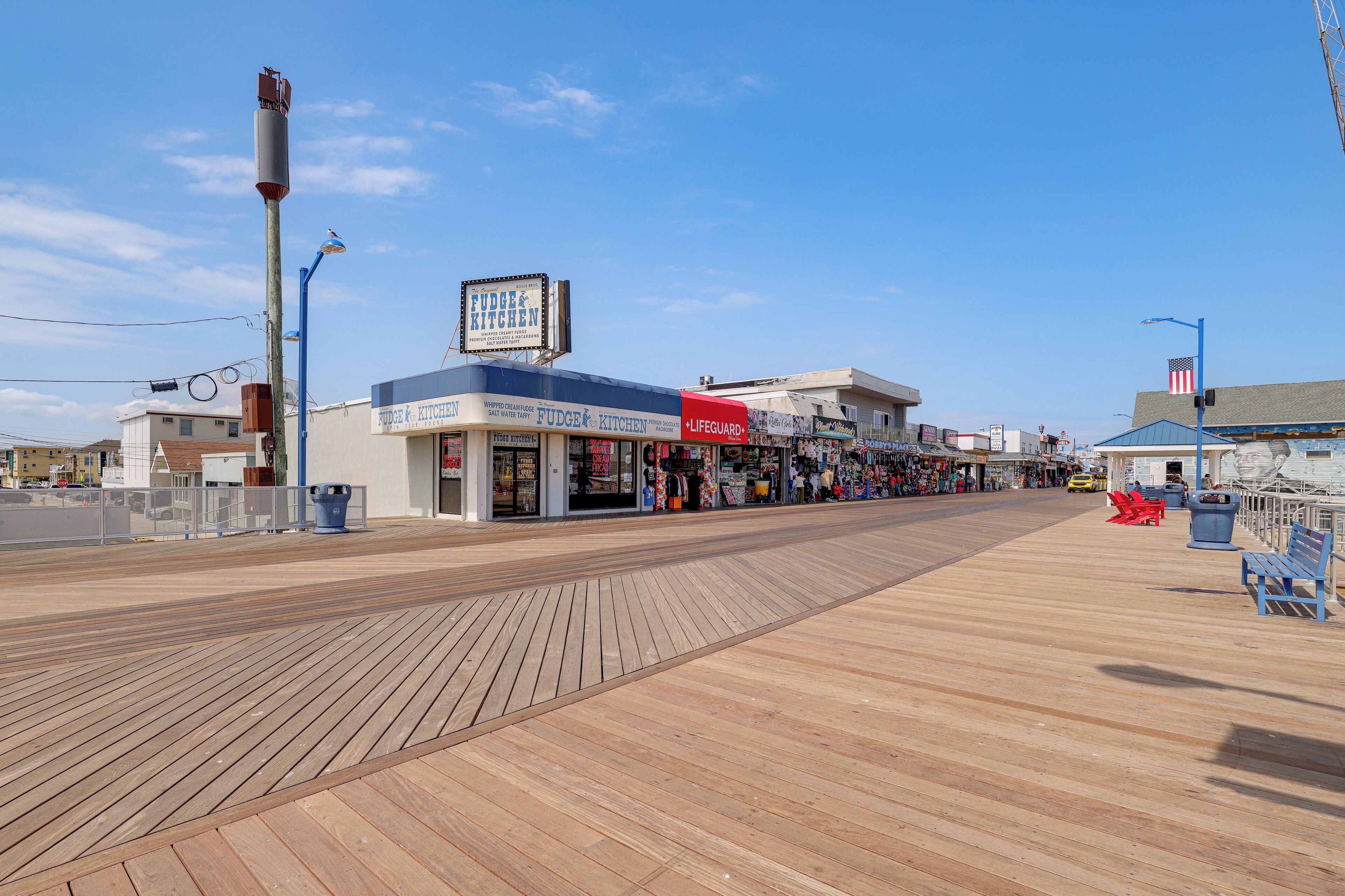 A boardwalk with shops, including a Fudge Kitchen, and a lifeguard stand.