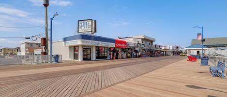 A boardwalk with shops, including a Fudge Kitchen, and a lifeguard stand.