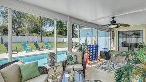 Um alpendre coberto com piscina, mobiliário de exterior e ventoinha no teto.