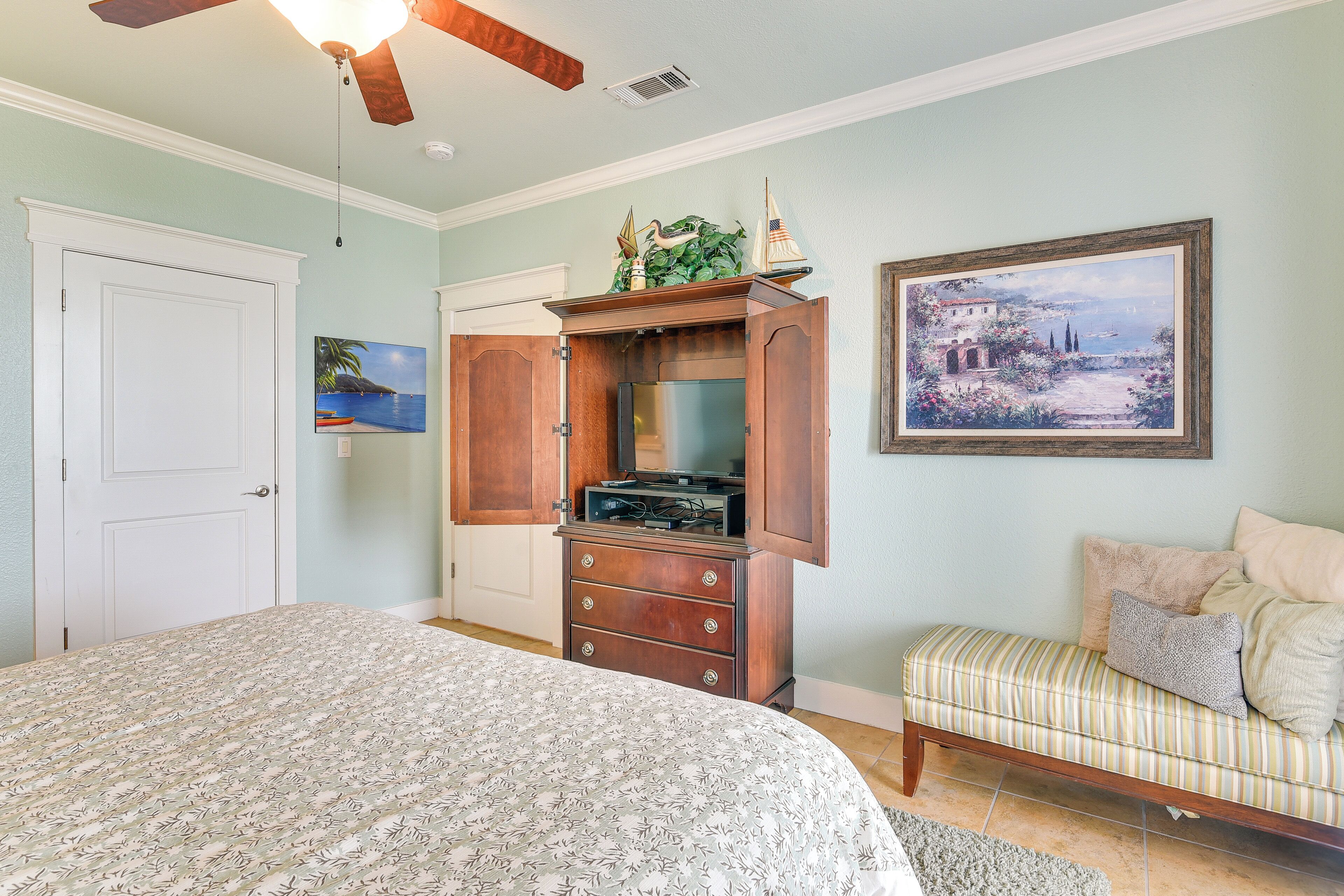 A bedroom with a bed, a dresser, a bench, and a painting on the wall.