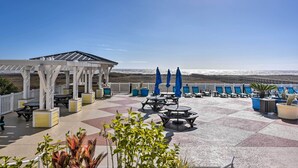 Een terras op het dak met buitenmeubilair, een pergola en uitzicht op het strand.