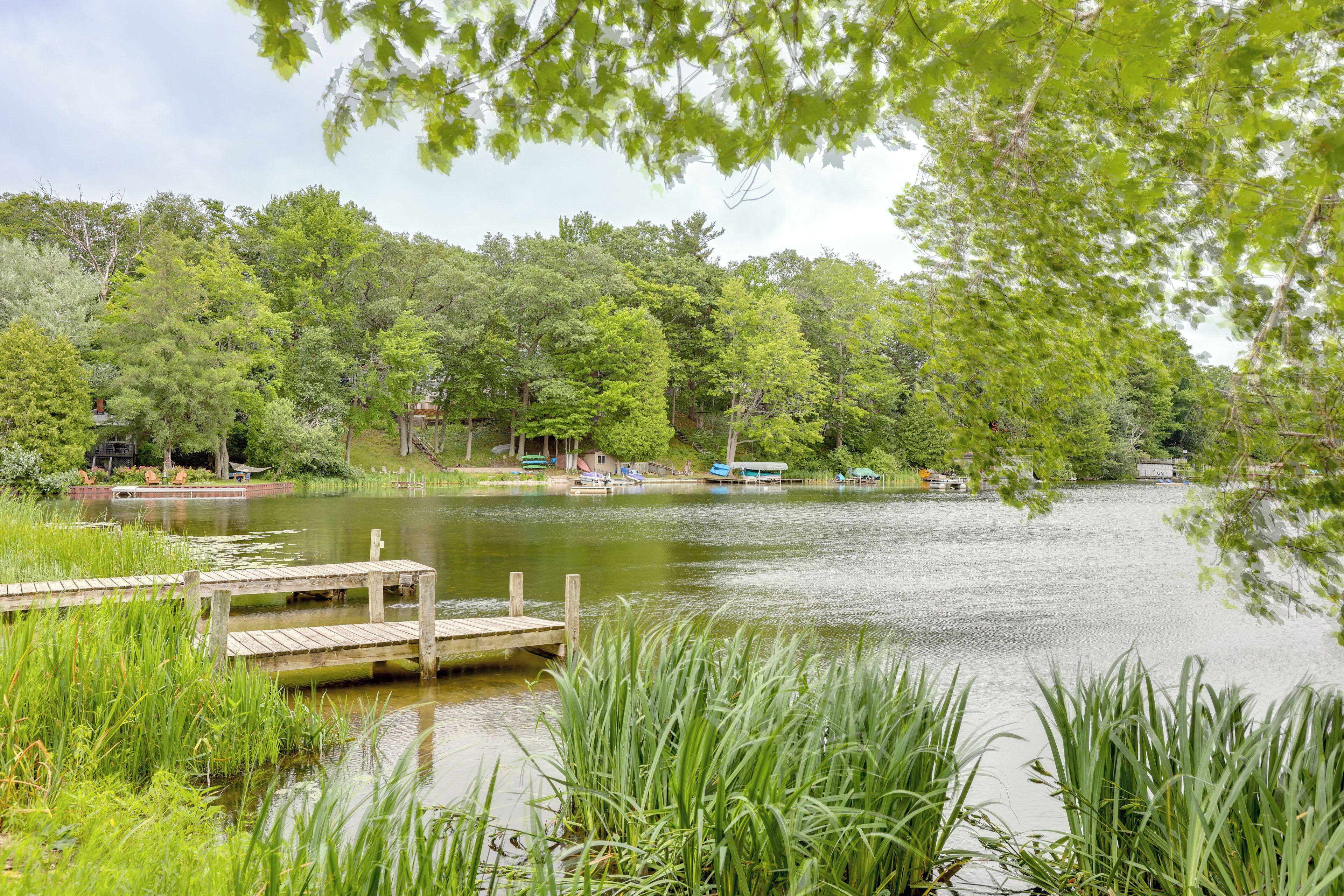 A serene lakeside setting with a wooden dock, lush greenery, and a small boat docked on the water.