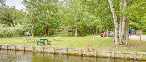 A park with a picnic table, benches, and a playground.