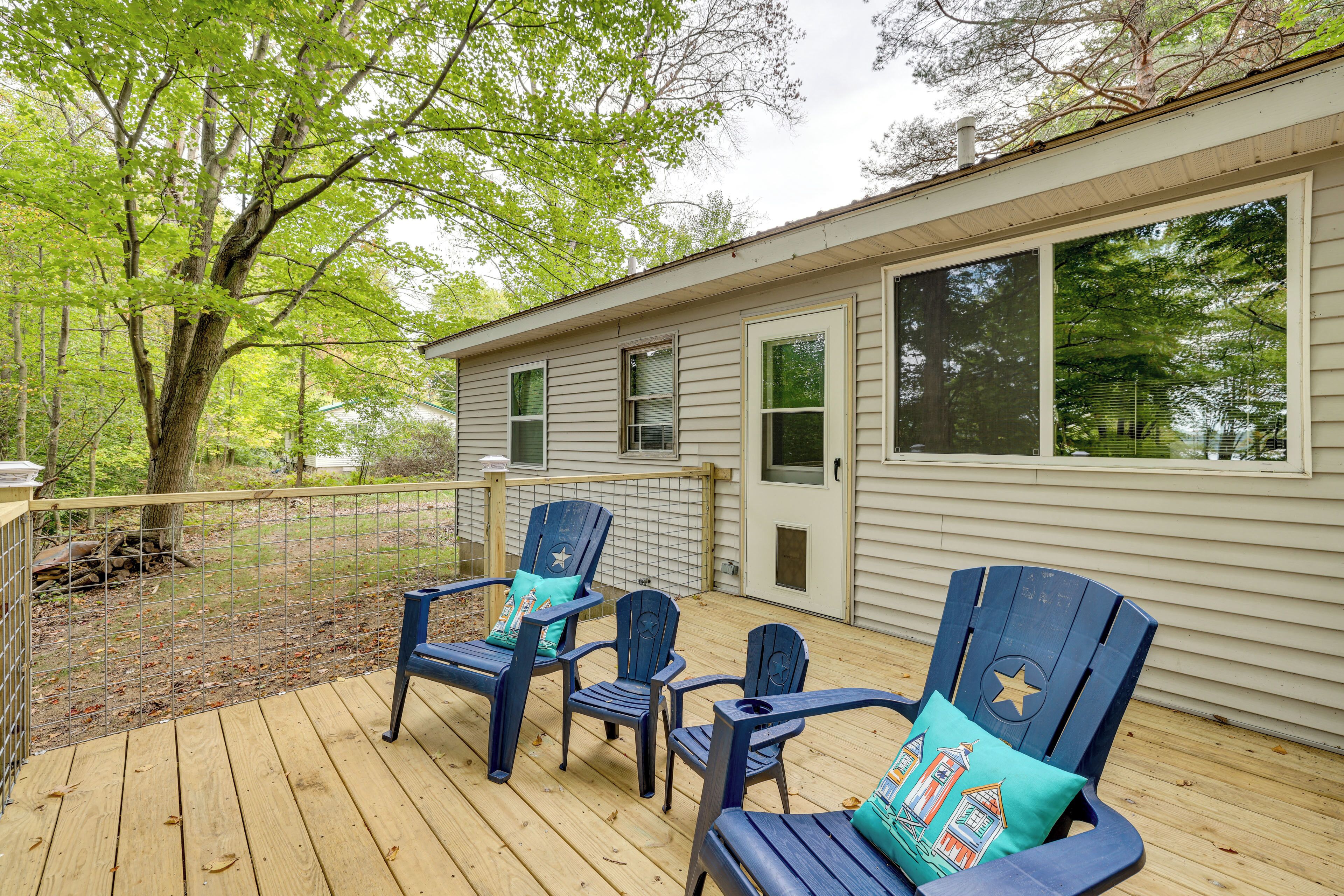 A wooden deck with four Adirondack chairs, each with a star-shaped pillow.