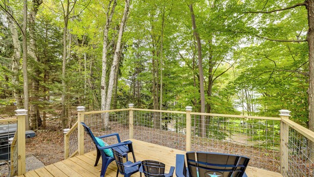 Eine Holzterrasse mit Sitzgelegenheiten und Blick auf einen Wald.