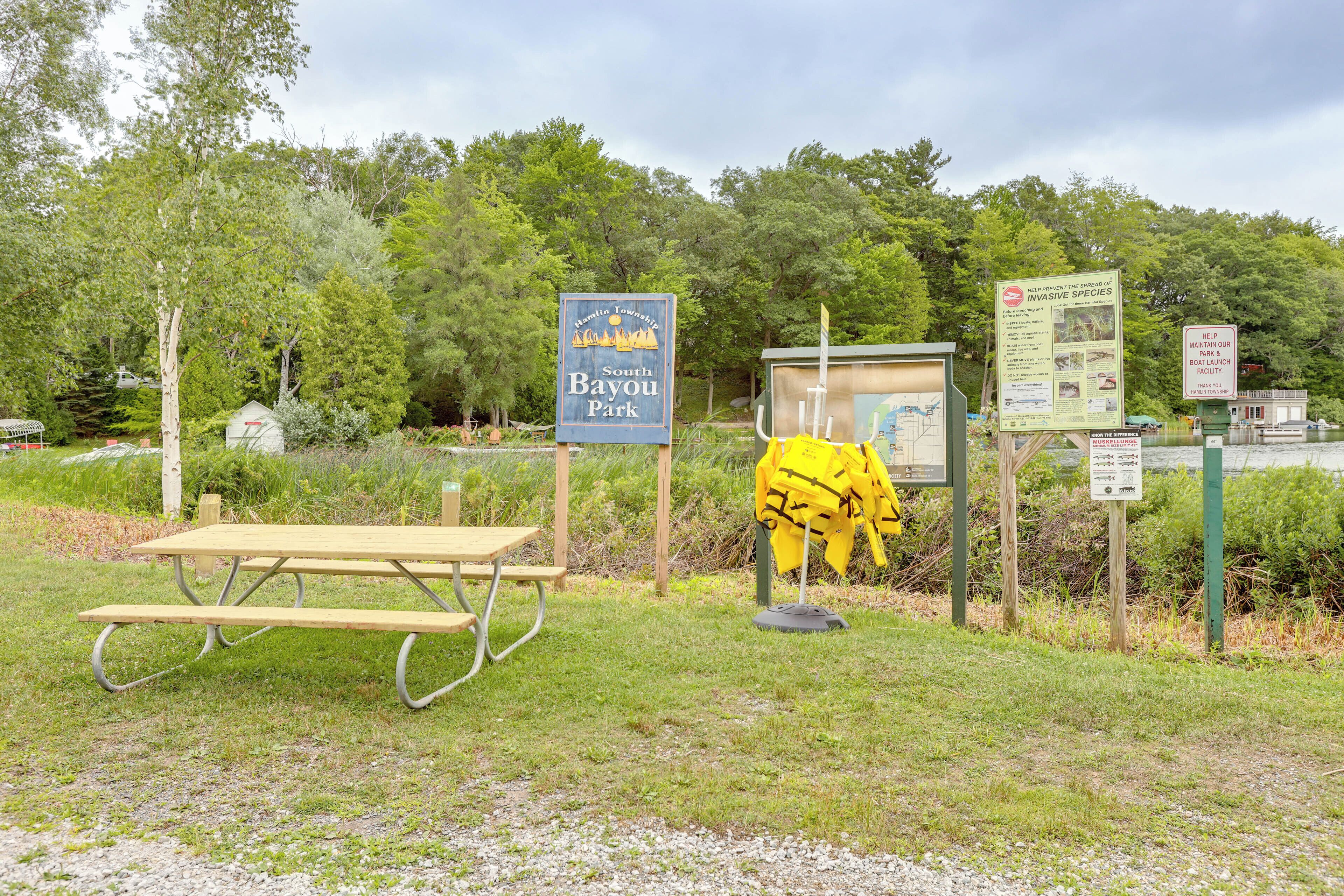 A picnic table, a sign for Hamlin Township South Bayou Park, and informational signs about invasive species.