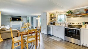Une cuisine moderne avec des meubles blancs, un four encastré et un coin repas comprenant des chaises et une table en bois.