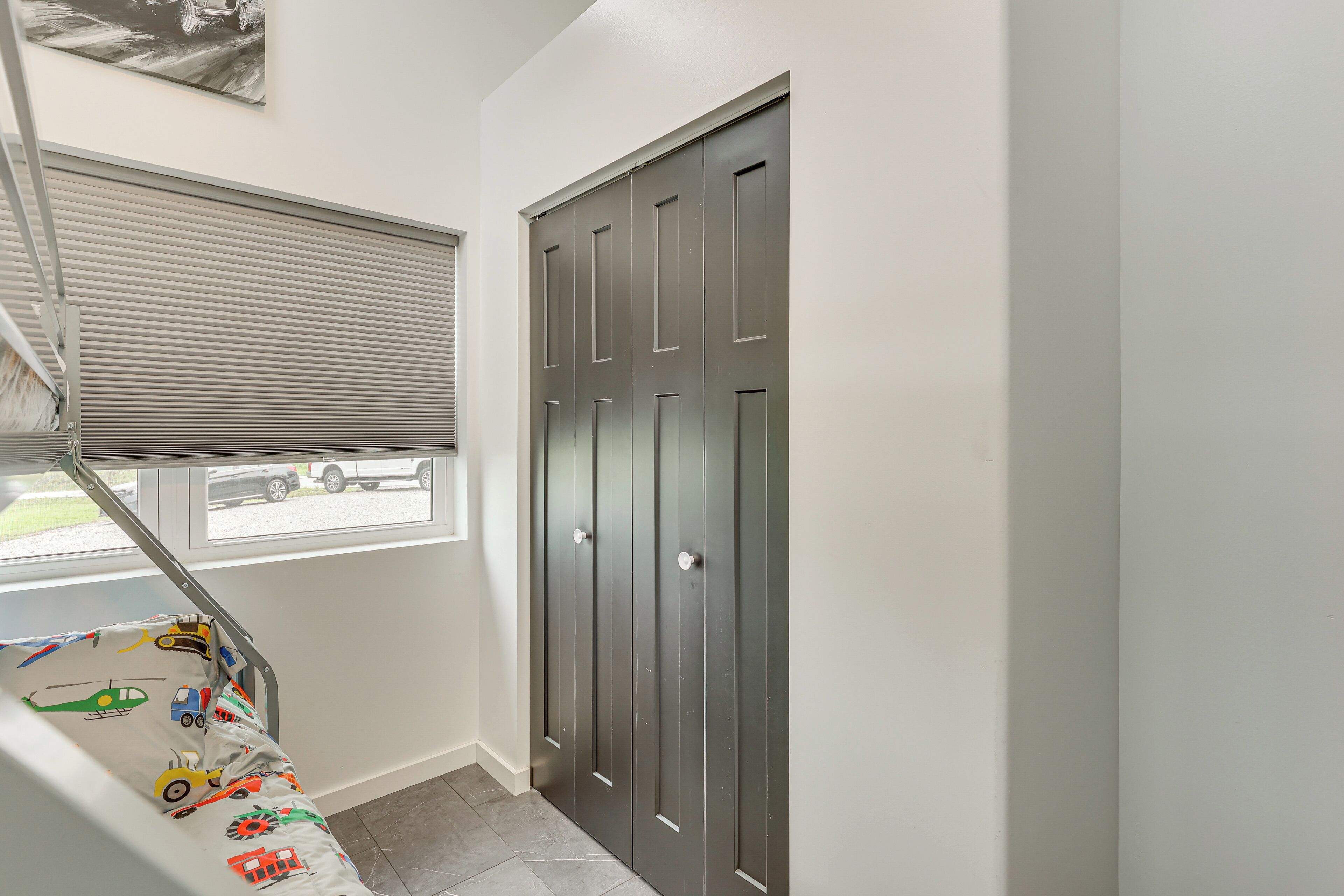 A staircase with a toy bed at the bottom, a window with blinds, and a dark door with a handle.