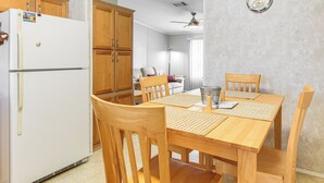 A dining area with a wooden table and chairs, a white refrigerator, wooden cabinets, and a ceiling fan. - Walk to Scenic Trails: Waterfront Okeechobee Oasis (Okeechobee)