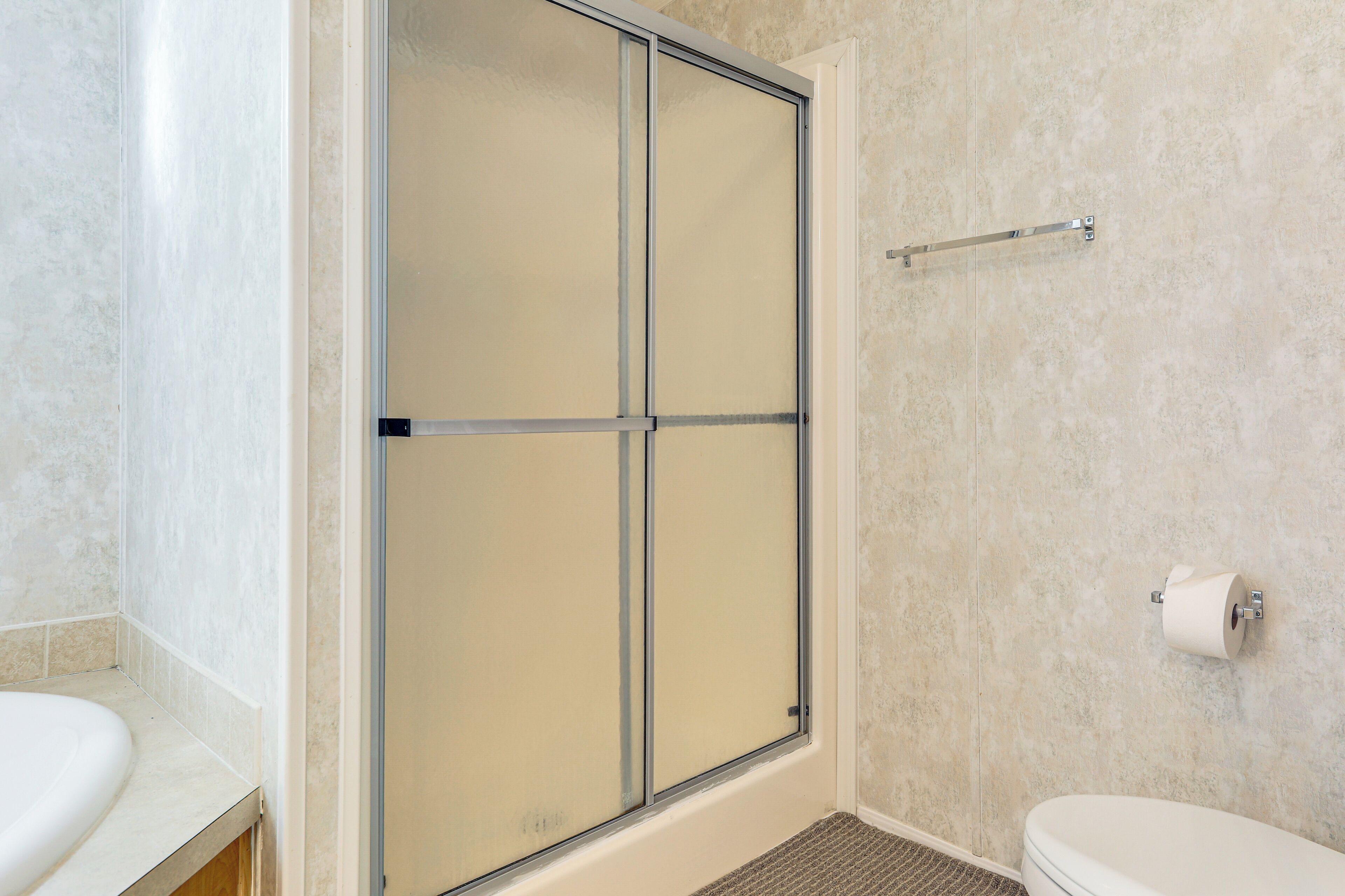 Une salle de bain avec une douche, des toilettes et un porte-serviettes.