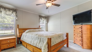 A bedroom with a wooden bed, a dresser, a television, and a ceiling fan. - Walk to Scenic Trails: Waterfront Okeechobee Oasis (Okeechobee)