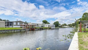 A canal with water lilies, a wooden bridge, and houses on either side. - Walk to Scenic Trails: Waterfront Okeechobee Oasis (Okeechobee)