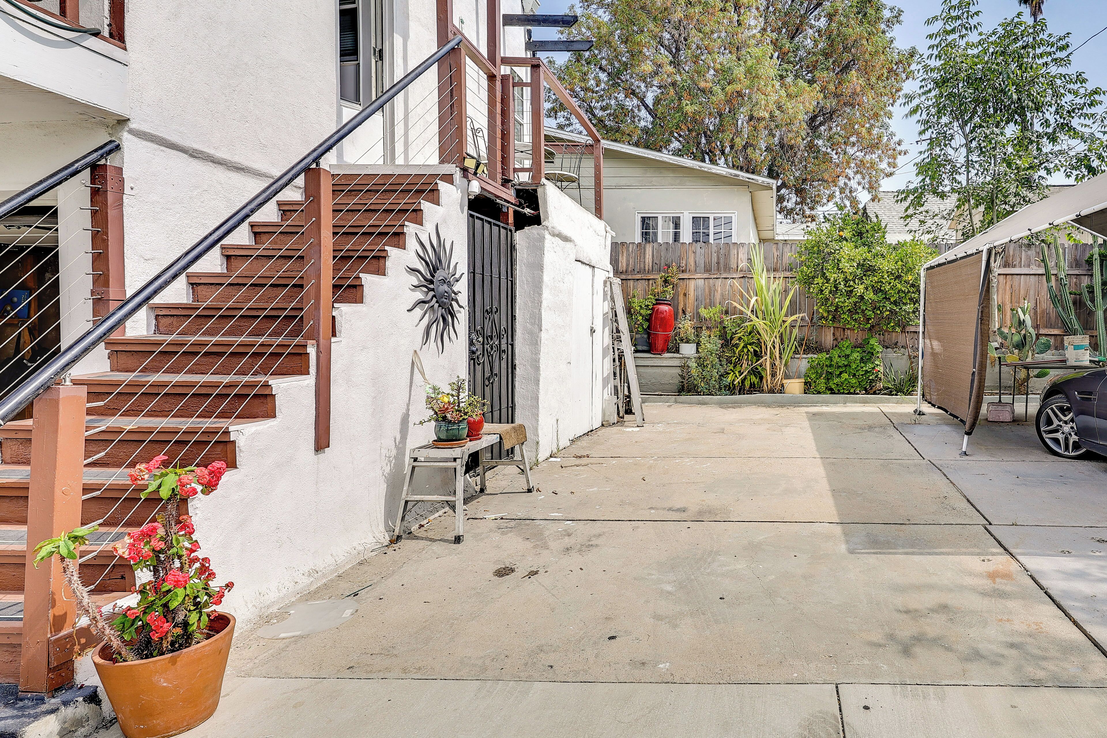 A residential property with a concrete driveway, a wooden staircase, and a fenced backyard.
