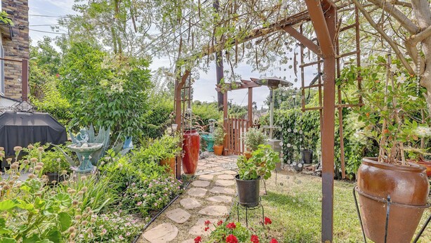 A garden with a stone pathway, potted plants, a pergola, and a large terracotta pot. - Fullerton Home Base: Easy Access to Dtwn + Csuf! (Fullerton)
