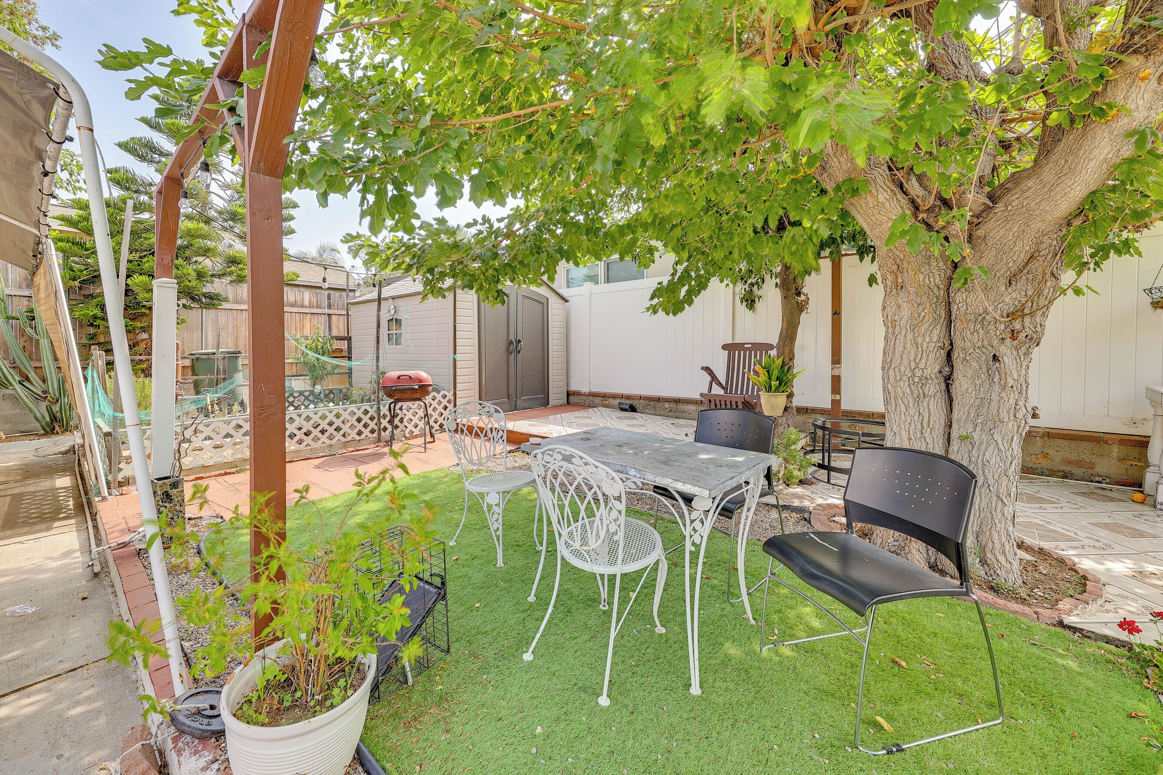 Un jardin avec une table et des chaises, une pergola et un arbre.