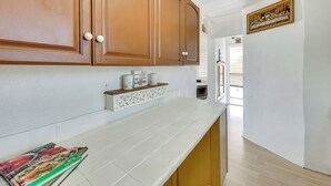 A kitchen with wooden cabinets, a white countertop, and a sign that reads "BUT FIRST Coffee." - Fullerton Home Base: Easy Access to Dtwn + Csuf! (Fullerton)
