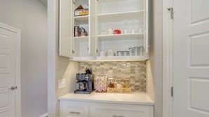 A kitchen with white cabinets, a coffee maker, and a coffee bar. - Modern Yukon Retreat: 2 Fireplaces, 14 Mi to OKC (Yukon)