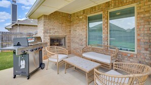 An outdoor patio with a grill, wicker furniture, and a brick wall. - Modern Yukon Retreat: 2 Fireplaces, 14 Mi to OKC (Yukon)