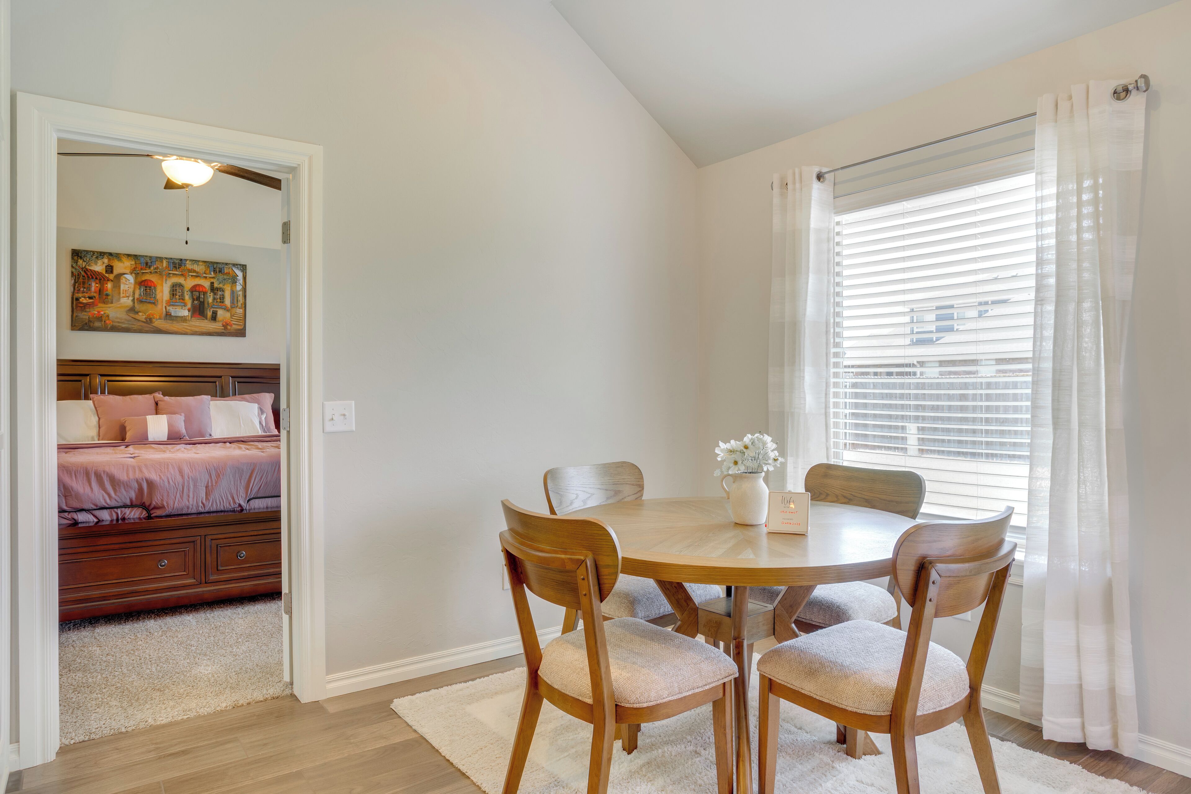 A dining area with a round wooden table, four wooden chairs, and a white rug.