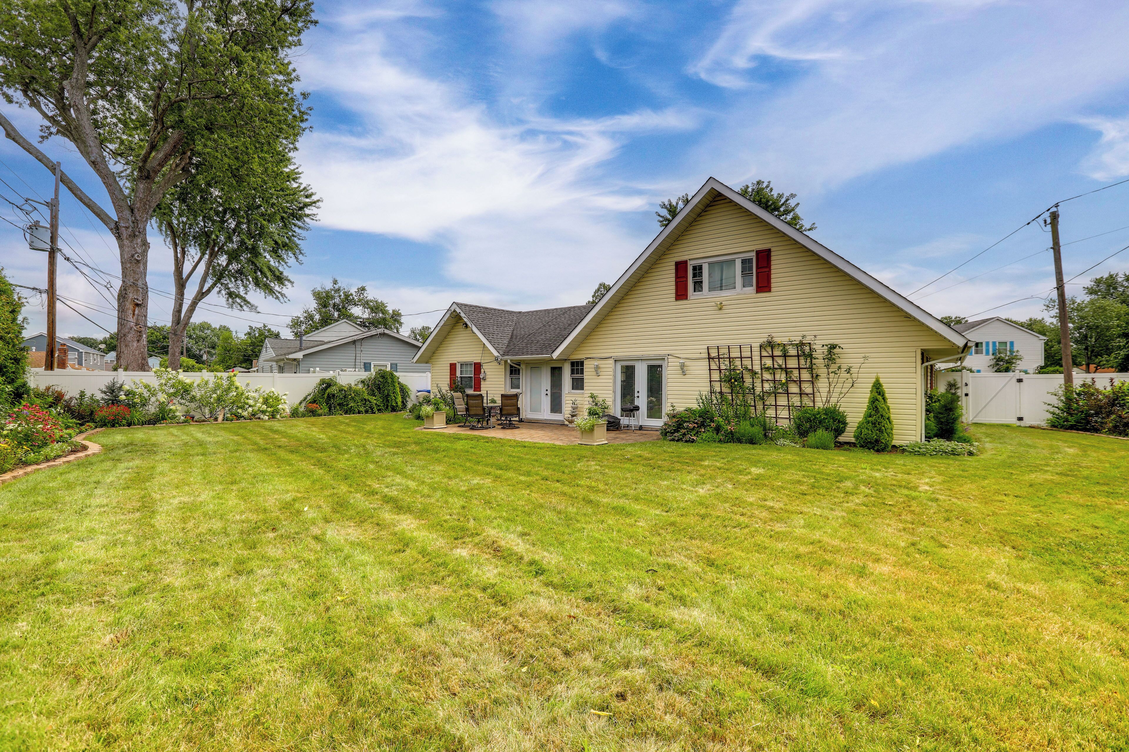 A single-story house with a well-maintained lawn, a patio with outdoor furniture, and a small garden area.