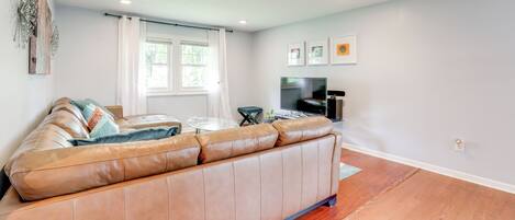 A living room with a large leather sofa, a flat-screen TV, and a coffee table.