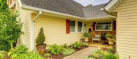A house with a covered porch, a small garden, and a window with shutters.