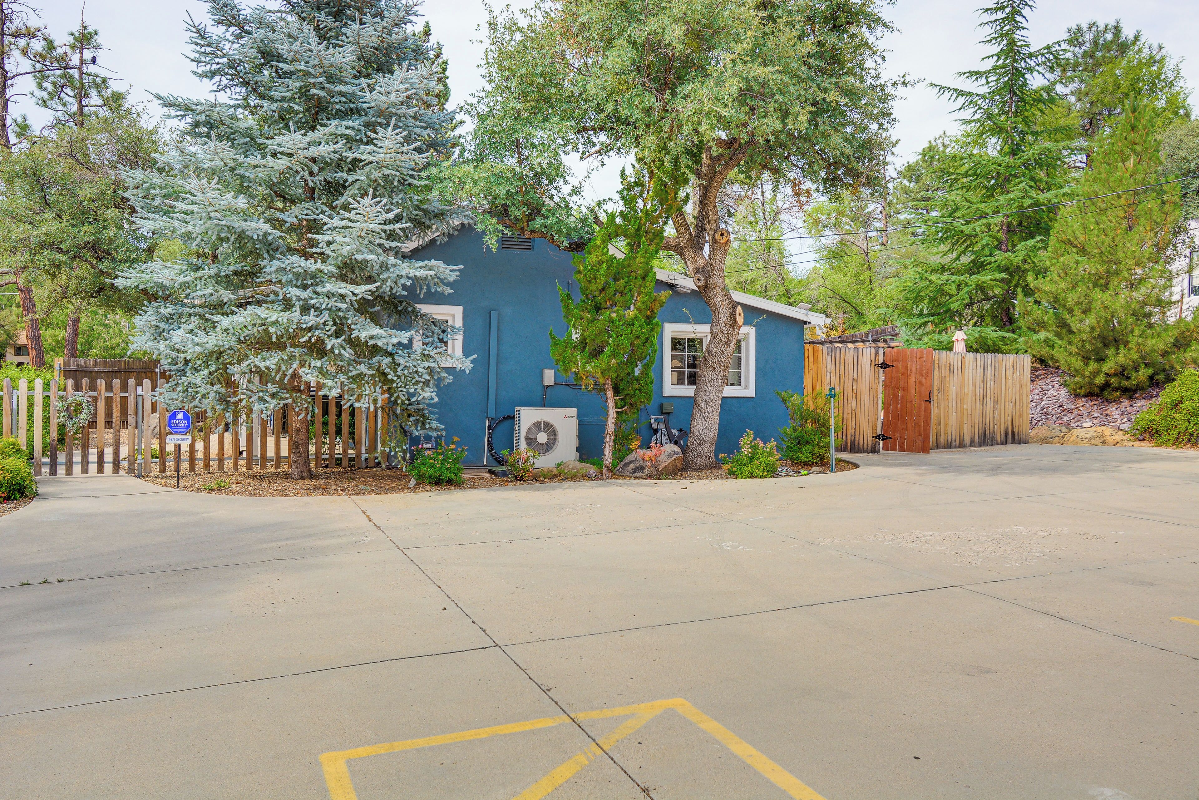A residential property with a blue house, a wooden fence, and a paved driveway.