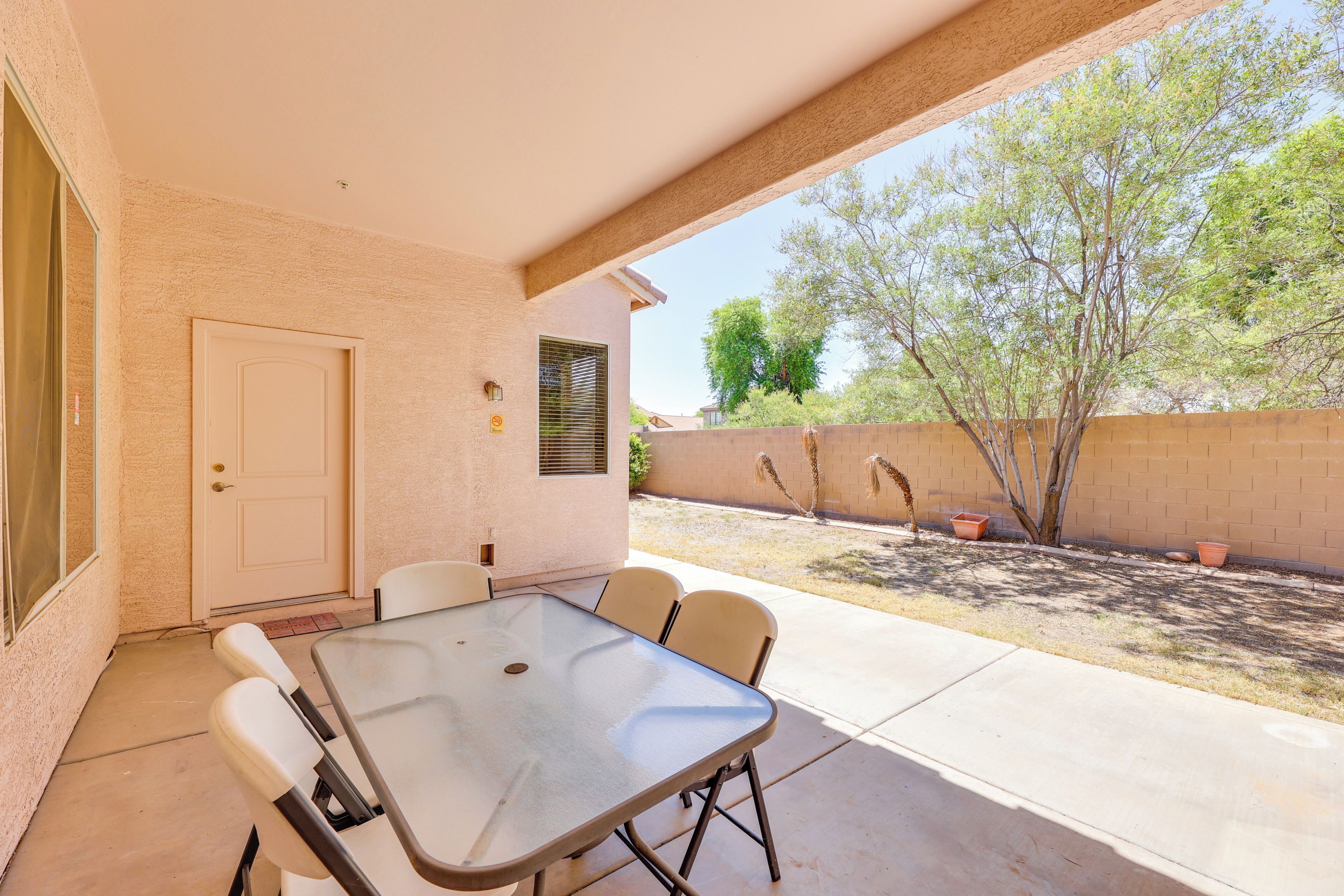 An outdoor patio with a table and chairs, a door, and a brick wall.