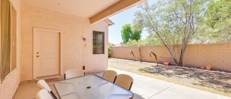 An outdoor patio with a table and chairs, a door, and a brick wall.