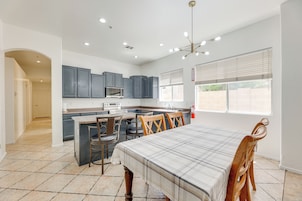 Una cocina moderna con armarios grises, una isla central y una zona de comedor con mesa y sillas.