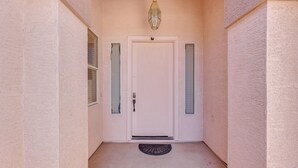 A white door with a small window and a doorbell, flanked by two vertical windows with blinds, and a light fixture above. - 3 Mi to Santan Village: Home w/ Covered Patio (Gilbert)