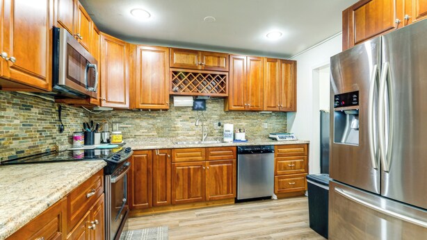 A modern kitchen with wooden cabinets, stainless steel appliances, and a brick backsplash. - 3 Mi to Dulles Airport: D.c. Area Townhome (Herndon)