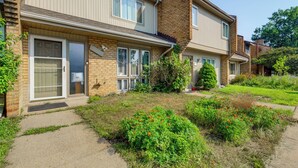 A two-story residential building with a brick facade, large windows, and a front yard with a small garden. - 3 Mi to Dulles Airport: D.c. Area Townhome (Herndon)