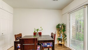A dining area with a wooden table and chairs, a plant on the table, and a sliding glass door to the right. - 3 Mi to Dulles Airport: D.c. Area Townhome (Herndon)