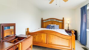 A wooden bed with a headboard, a nightstand with a lamp, a dresser with drawers, and a ceiling fan. - 3 Mi to Dulles Airport: D.c. Area Townhome (Herndon)