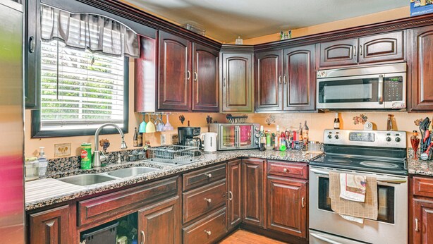 Una cocina con armarios de madera oscura, un microondas de acero inoxidable y un horno doble.