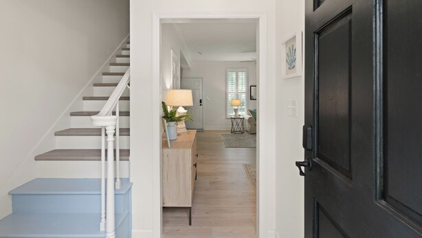A staircase with white railings and wooden steps leading to a room with a light-colored wooden floor. - Charming Condo Across the Street from the Beach (St Simons Island)