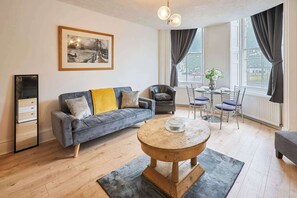 A modern living room with a sofa, coffee table, and dining area. - Host & Stay | Grand Parade Apartment (Brighton and Hove)
