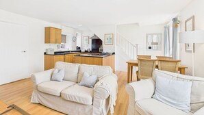 A modern living room with a sofa and a dining area with wicker chairs. - Host & Stay | Dove Cottage (Warkworth)
