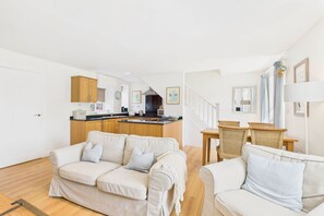A modern living room with a sofa and a dining area with wicker chairs. - Host & Stay | Dove Cottage (Warkworth)