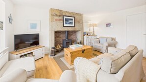 A living room with a television, a fireplace, a sofa, and a wooden coffee table. - Host & Stay | Dove Cottage (Warkworth)